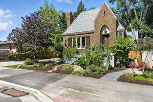 Tudor home featuring a shingled roof, brick siding, and a chimney