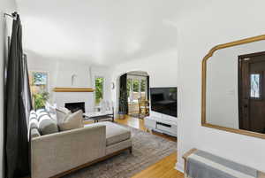 Living room featuring arched walkways, wood finished floors, and a fireplace