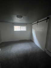 Unfurnished bedroom with carpet flooring and a barn door