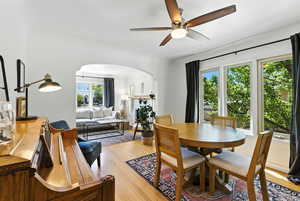 Dining area featuring arched walkways, a ceiling fan, healthy amount of natural light, and light wood-type flooring