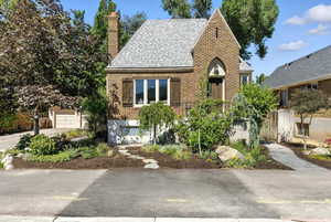 Tudor-style house with brick siding, a shingled roof, and a chimney
