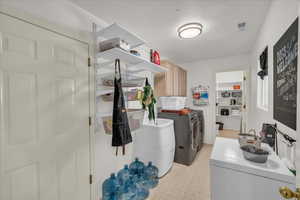 Washroom featuring separate washer and dryer, light floors, and cabinet space