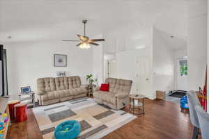 Living room with wood finished floors, ceiling fan, and high vaulted ceiling