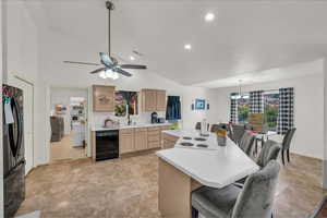 Kitchen featuring black appliances, light brown cabinets, light countertops, a chandelier, and vaulted ceiling