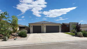 View of front of house with an attached garage, stucco siding, driveway, and a tile roof Ssmmer 2025