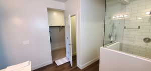 Full bath with walk in shower, wood finished floors, and a walk in closet