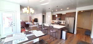 Kitchen with stainless steel appliances, light countertops, a breakfast bar, dark brown cabinetry, and open floor plan