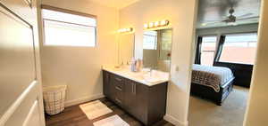Ensuite bathroom with double vanity, a ceiling fan, and wood finished floors