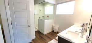 Bathroom with a walk in shower, double vanity, and wood finished floors