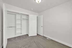 Unfurnished bedroom featuring carpet flooring, a closet, and a textured ceiling