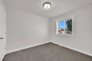 Spare room featuring dark colored carpet and a textured ceiling