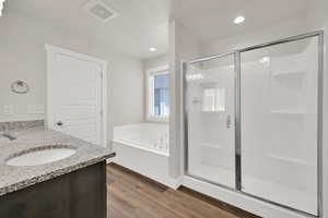 Full bath with a stall shower, wood finished floors, a garden tub, vanity, and recessed lighting