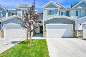 View of front of home featuring driveway, board and batten siding, stone siding, and an attached garage