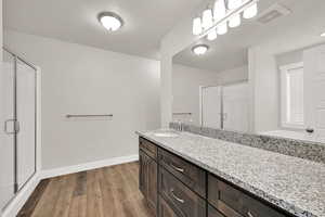 Bathroom featuring a stall shower, vanity, and wood finished floors