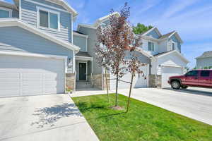 View of front of home featuring driveway, stone siding, and a front yard