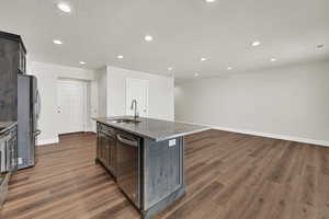 Kitchen featuring appliances with stainless steel finishes, dark wood finished floors, recessed lighting, dark stone counters, and a textured ceiling