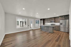Kitchen with appliances with stainless steel finishes, recessed lighting, dark wood-style flooring, dark brown cabinetry, and light countertops