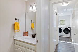 Guest Bathroom with washing machine and clothes dryer, vanity, and wood finished floors