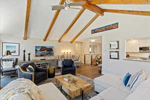 Living room with ceiling fan, wood finished floors, high vaulted ceiling, and beamed ceiling