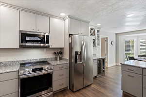Kitchen with stainless steel appliances, gray cabinetry, wine cooler, dark wood finished floors, and a textured ceiling