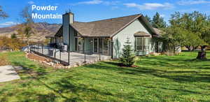 Back of house featuring a deck with mountain view, a yard, and a chimney