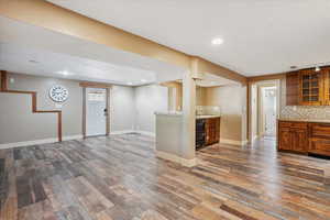 Aparmtnet Dining, living andKitchen with brown cabinetry, dark wood-type flooring, tasteful backsplash, and recessed lighting