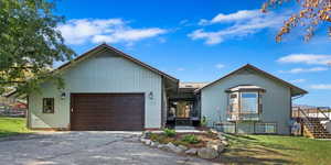 View of front of house featuring stairway, an attached garage, driveway, and a front yard