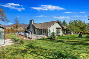 Back of house with a chimney, a lawn, and a deck with mountain view
