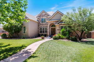 Traditional home featuring stone siding, a front lawn, stucco siding, and a tile roof