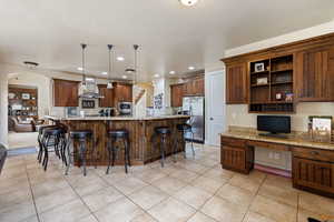 Kitchen with wall chimney exhaust hood, stainless steel appliances, built in desk, recessed lighting, and arched walkways