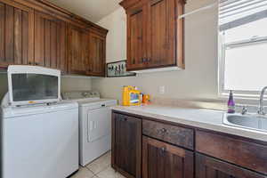 Laundry room with cabinet space, washer and dryer, and light tile patterned flooring
