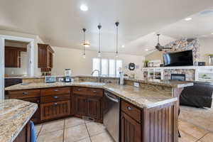 Kitchen featuring stainless steel dishwasher, light tile patterned floors, ceiling fan, lofted ceiling, and a kitchen breakfast bar