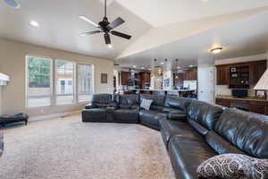 Carpeted living area with vaulted ceiling, ceiling fan, and recessed lighting
