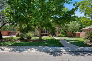 View of property hidden behind natural elements with stucco siding