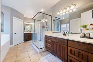 Bathroom featuring a shower stall, tile patterned floors, vanity, and a garden tub