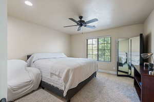 Bedroom with light colored carpet and a ceiling fan