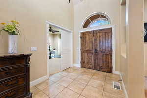 Entryway with ceiling fan, a towering ceiling, and light tile patterned floors