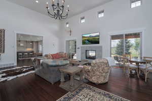 Living room with hardwood / wood-style floors, a towering ceiling, a premium fireplace, and a chandelier