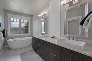 Full bath featuring double vanity, a freestanding tub, and tile patterned flooring
