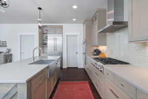 Kitchen with wall chimney exhaust hood, stainless steel appliances, light countertops, open shelves, and recessed lighting