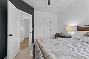 Bedroom with a ceiling fan, light wood-style floors, a closet, and light carpet