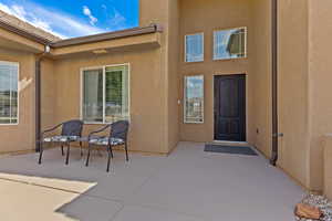 View of exterior entry with a patio and stucco siding
