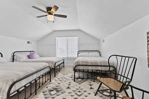 Bedroom with light carpet, vaulted ceiling, and a ceiling fan