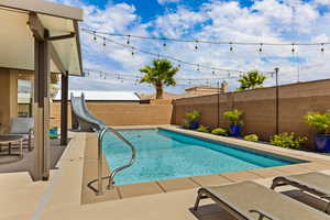 View of pool with a water slide, a fenced backyard, and a patio area