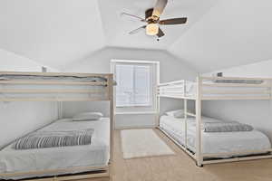 Carpeted bedroom with vaulted ceiling and ceiling fan