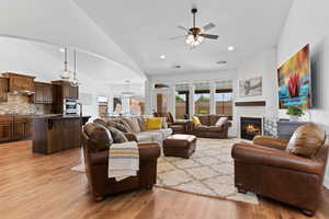 Living area featuring ceiling fan, light wood-style floors, a tile fireplace, arched walkways, and recessed lighting