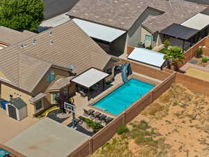 View of pool featuring a patio area, a fenced backyard, a storage shed, and a water slide