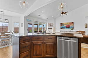Kitchen with dishwasher, open floor plan, dark stone countertops, light wood finished floors, and vaulted ceiling