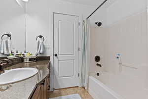 Bathroom featuring vanity, shower / bath combination with curtain, and tile patterned flooring