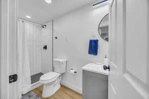 Full bath with vanity, wood finished floors, tiled shower, and recessed lighting